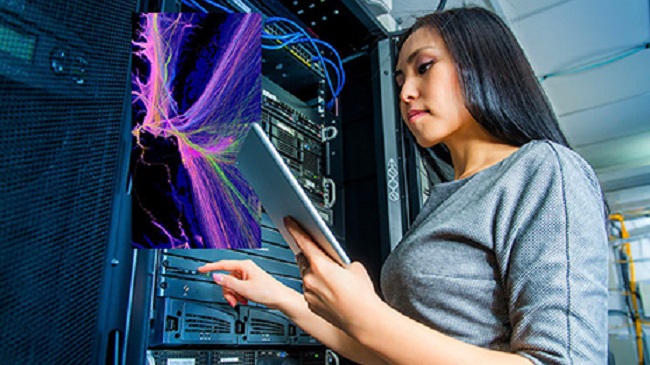 A lady operating a server rack while looking at a tablet